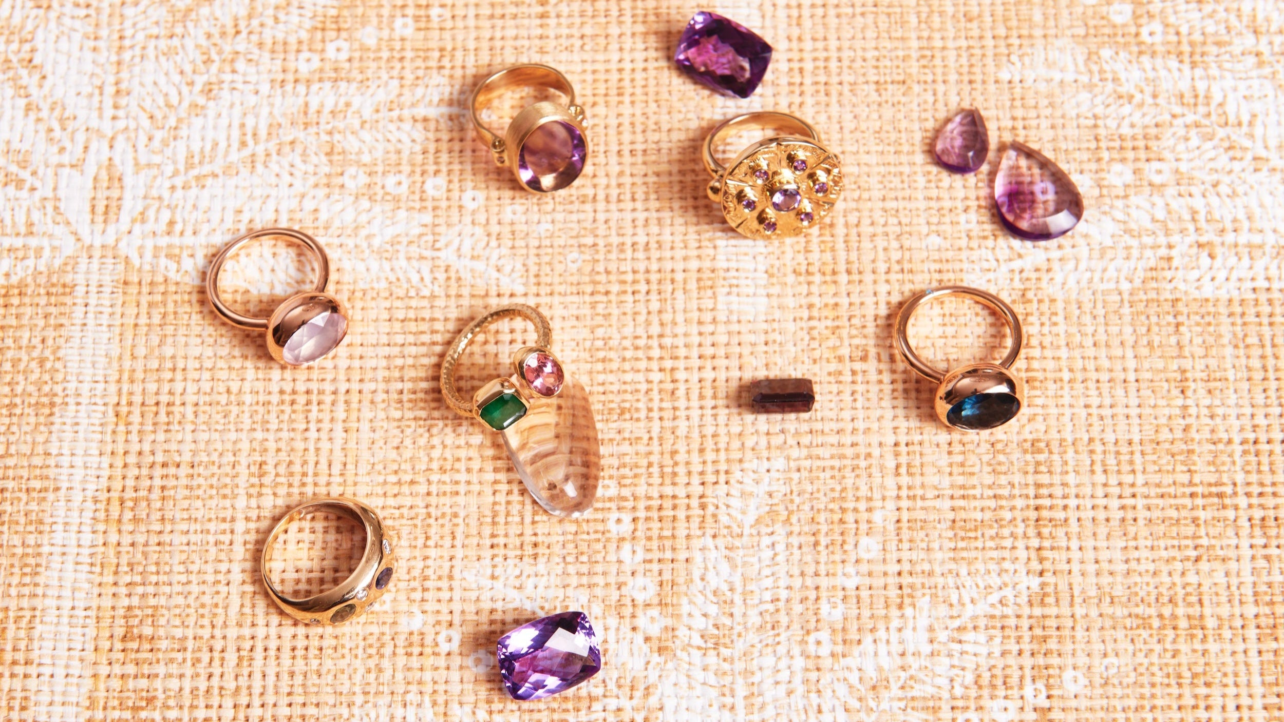 Gold rings with gemstones on a textured beige surface