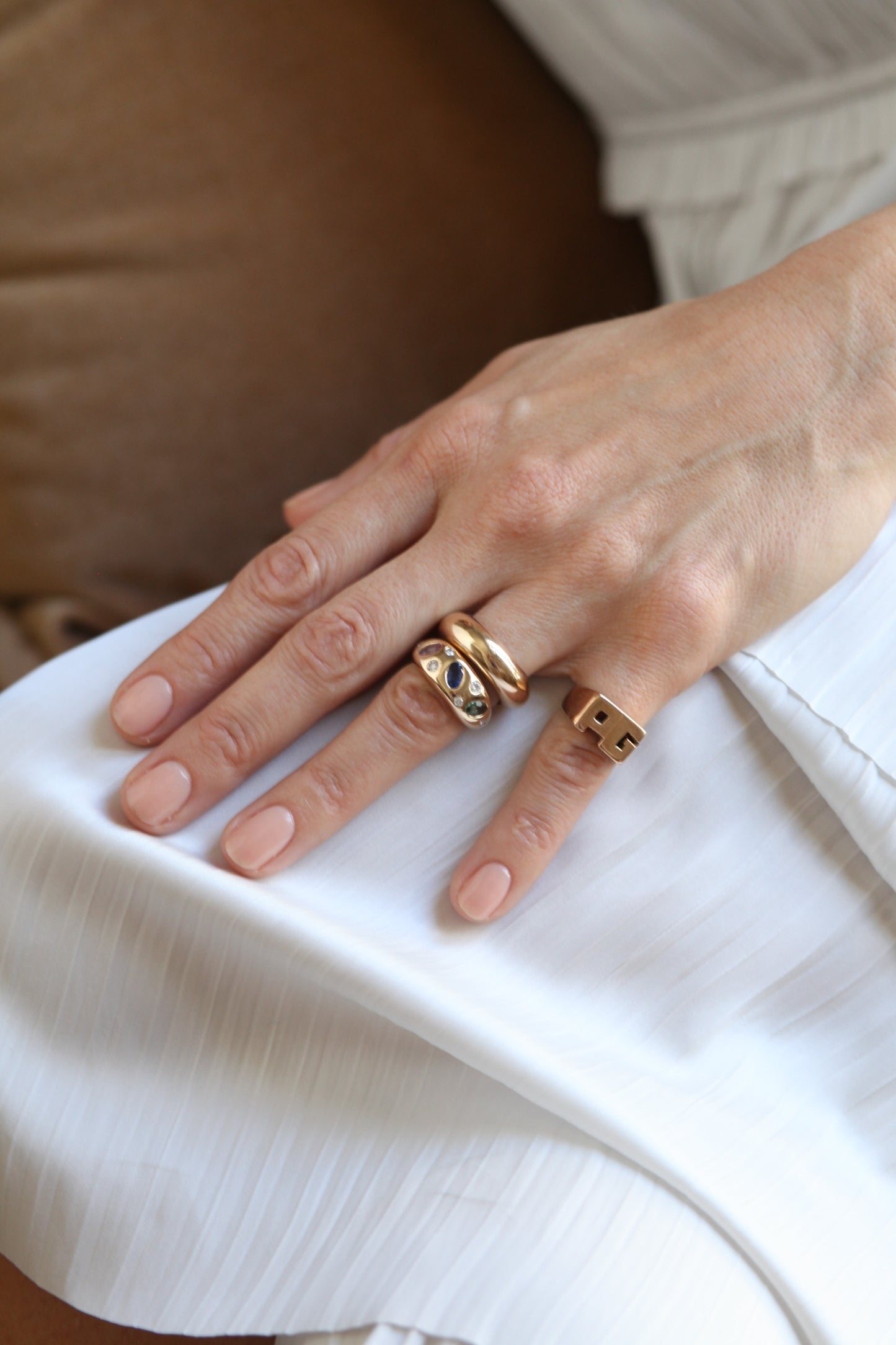 Close-up of a hand wearing gold rings on a white fabric background