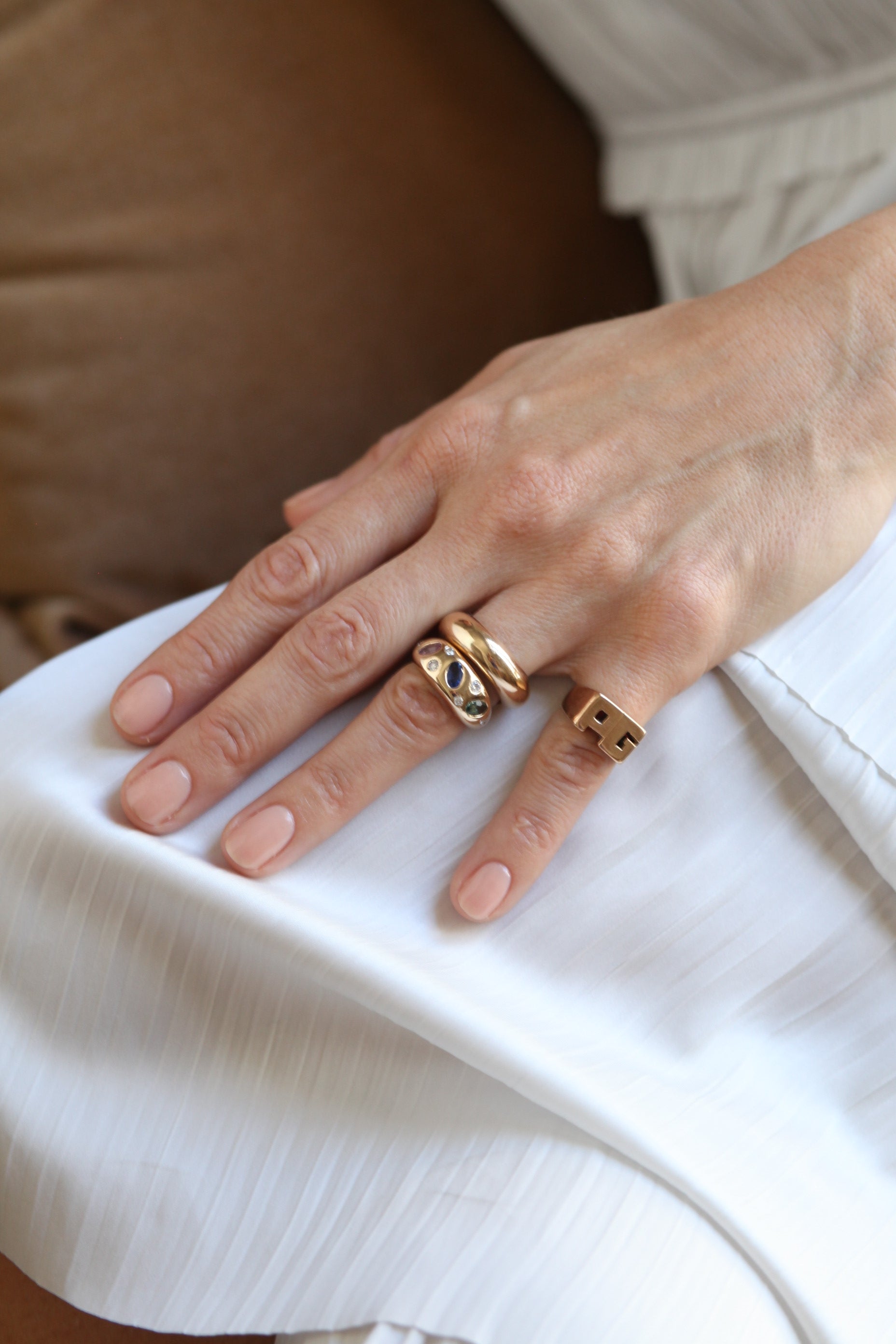 Close-up of a hand wearing gold rings on a white fabric background