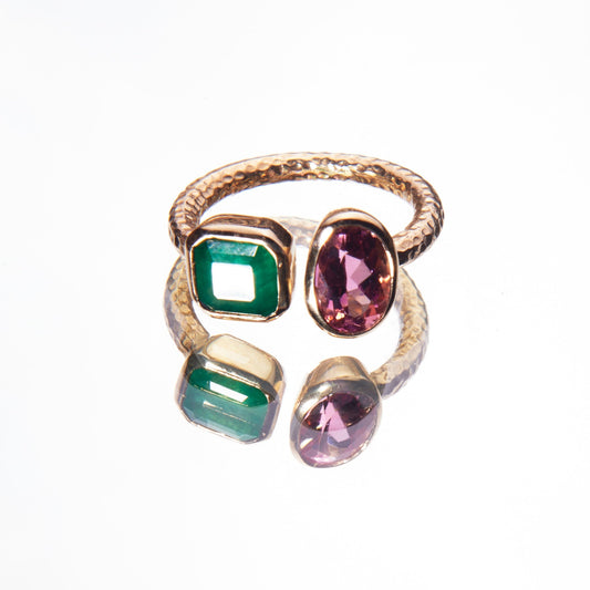 Gold ring with green and pink gemstones on a white background