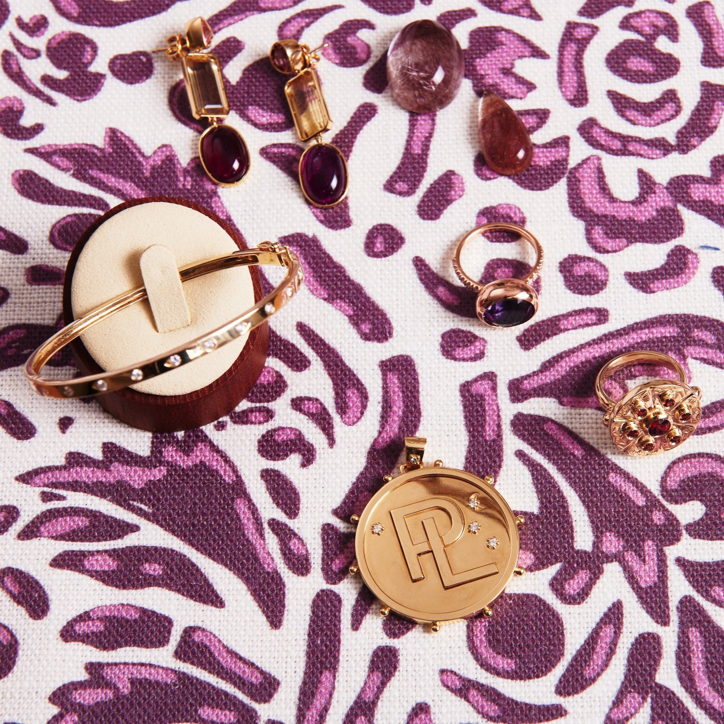 Collection of gold and gemstone rings on a purple patterned fabric background